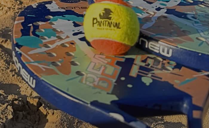 Raquete e bolinha de beach tennis sobre a areia